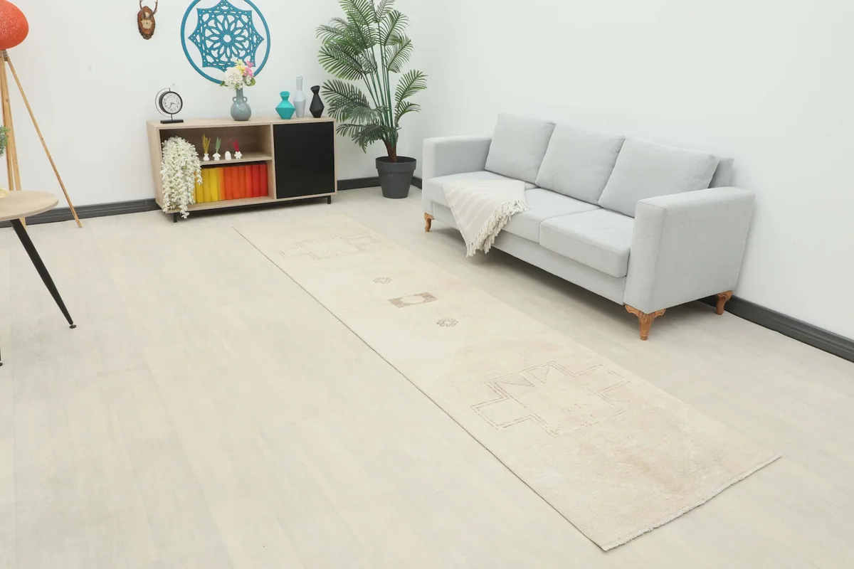 Beige and tan runner rug in a room setting, extending from a console to a sofa