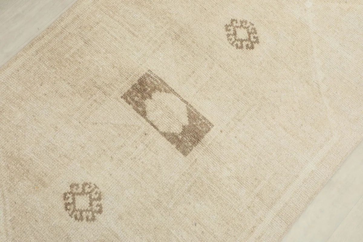 Close-up of central tan geometric and tribal motifs on the beige runner rug