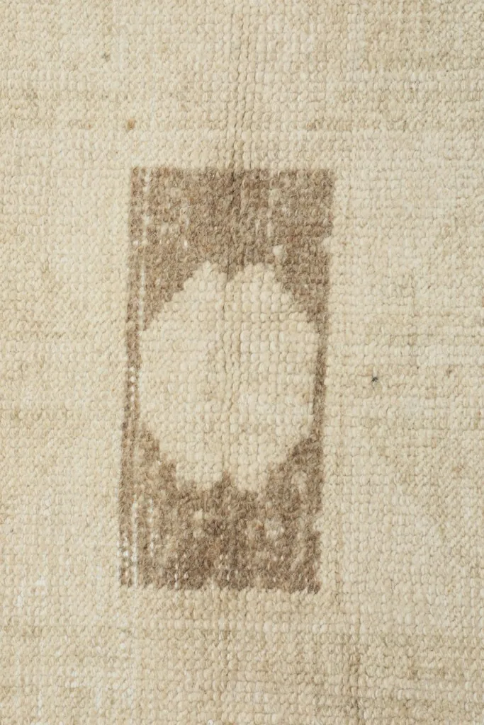 Detailed view of a rectangular tan motif with a lighter center on the rug