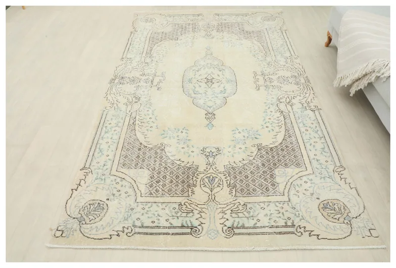 Full overhead view of the 5x8 vintage Anatolian rug with an ivory field and blue medallion