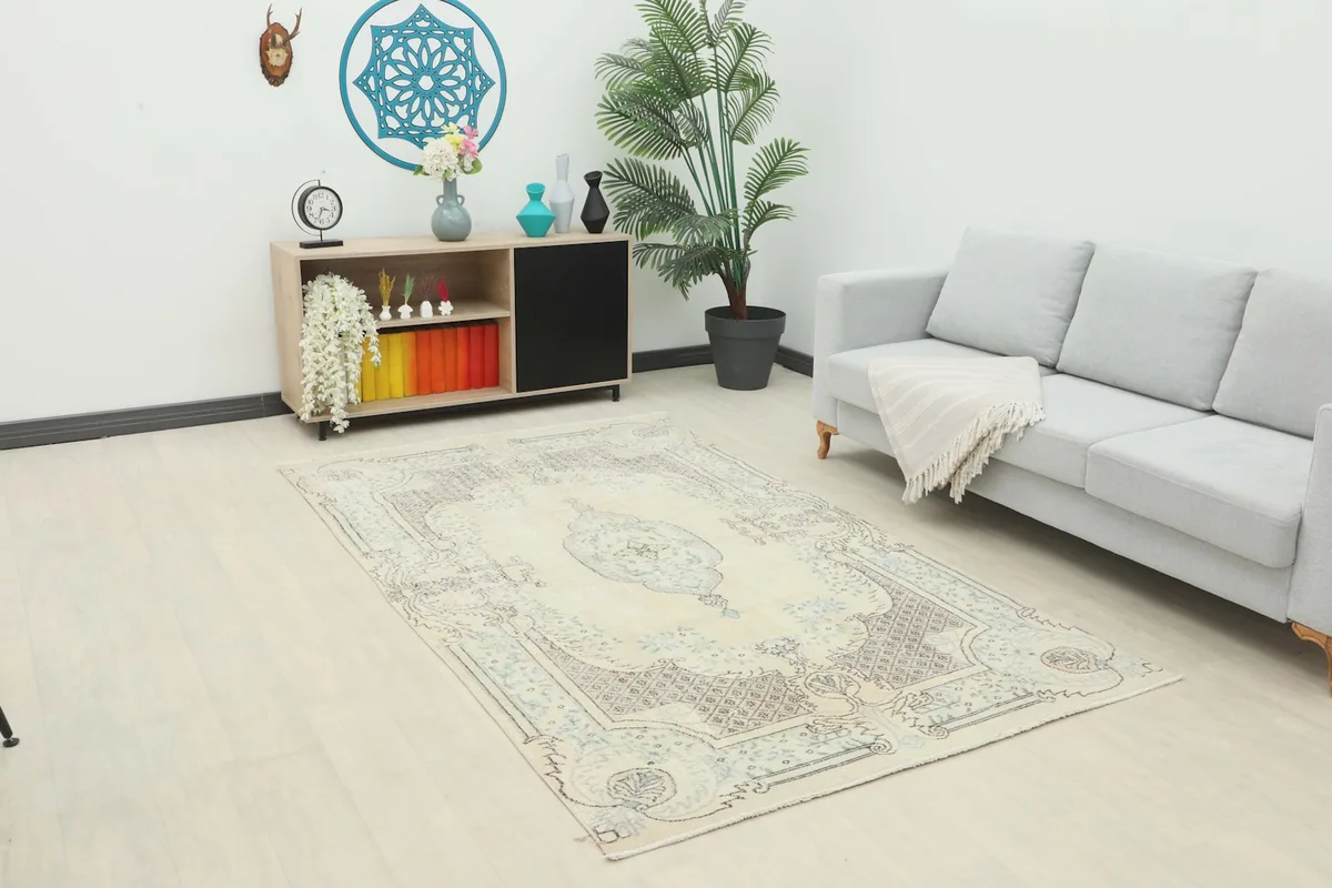 Medium ivory and blue vintage rug placed in a living room setting with a gray sofa