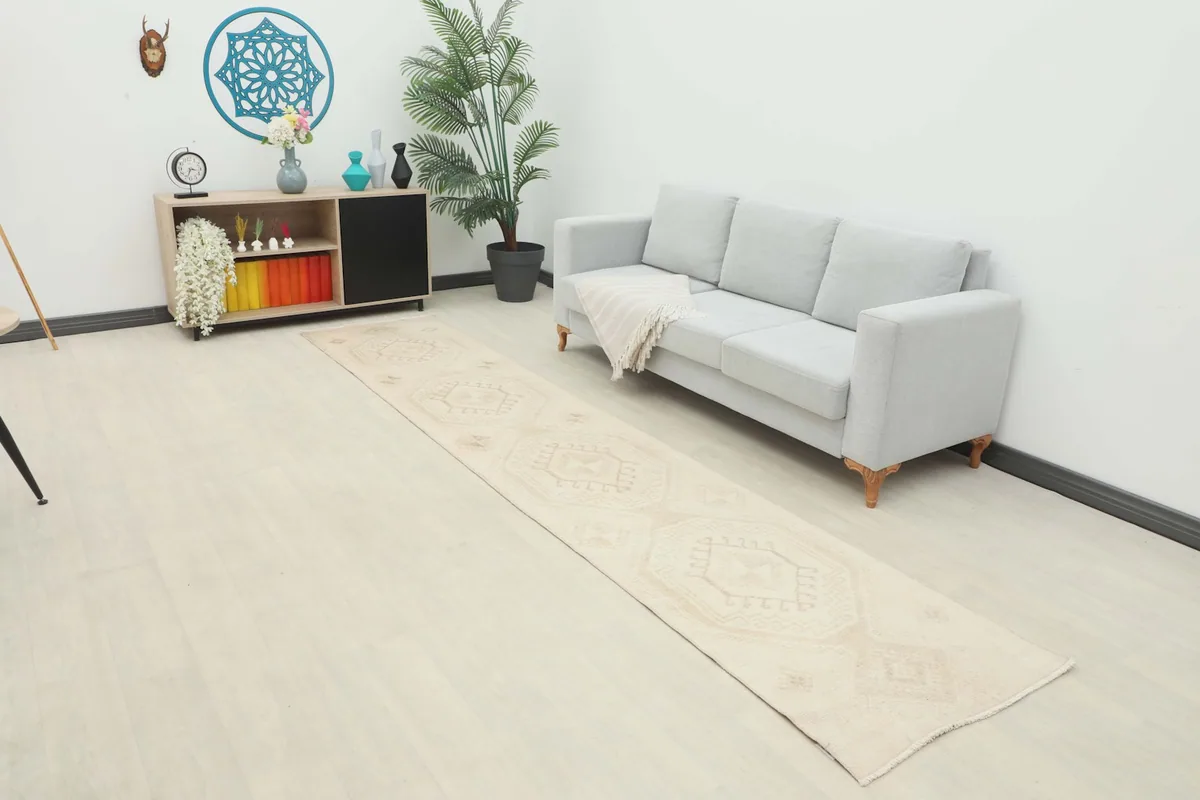 Runner rug laid out in a modern living space with a light gray sofa and wooden floors.