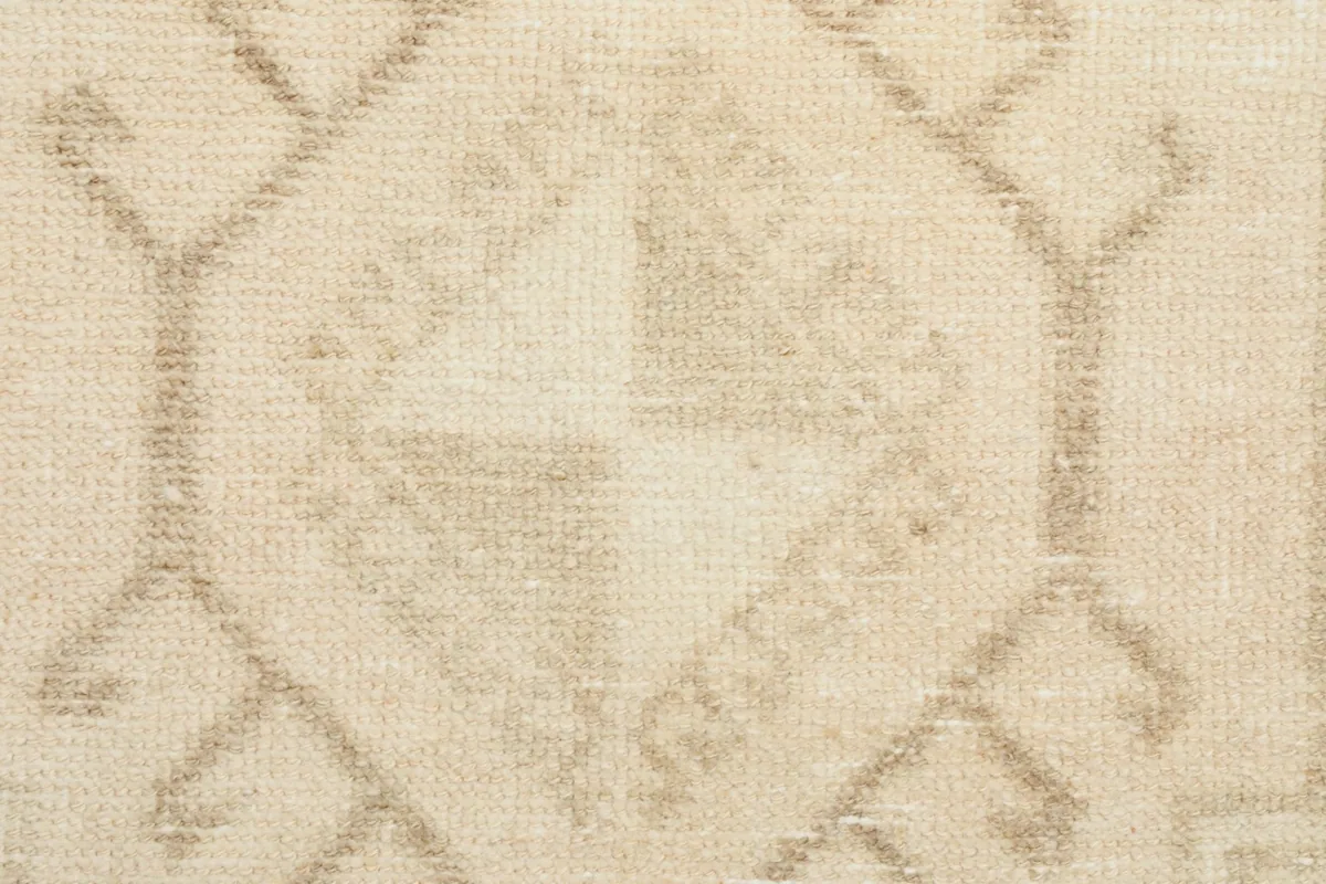 Extreme close-up of the hand-knotted wool pile, showing the texture and faded beige pattern.