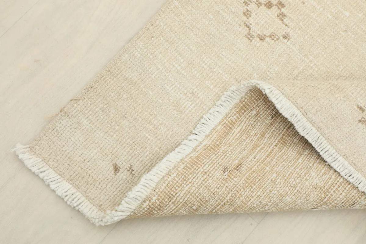 Corner of the rug folded back, showing the cotton foundation and fringes