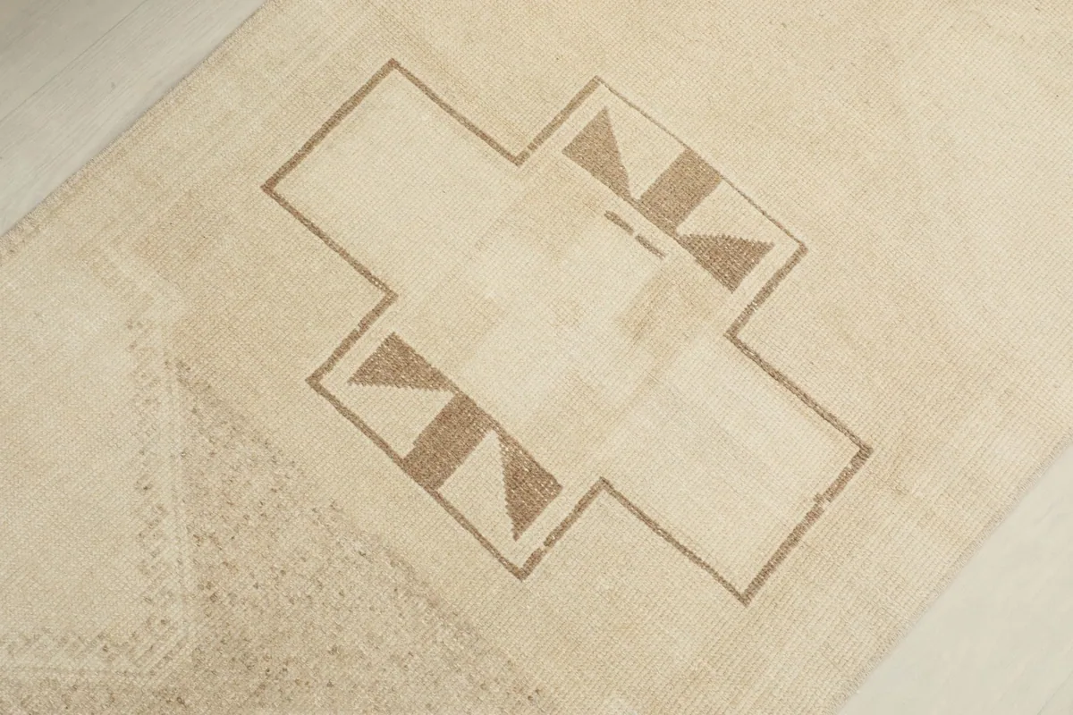Close-up of a central geometric motif in brown and tan against the ivory background.