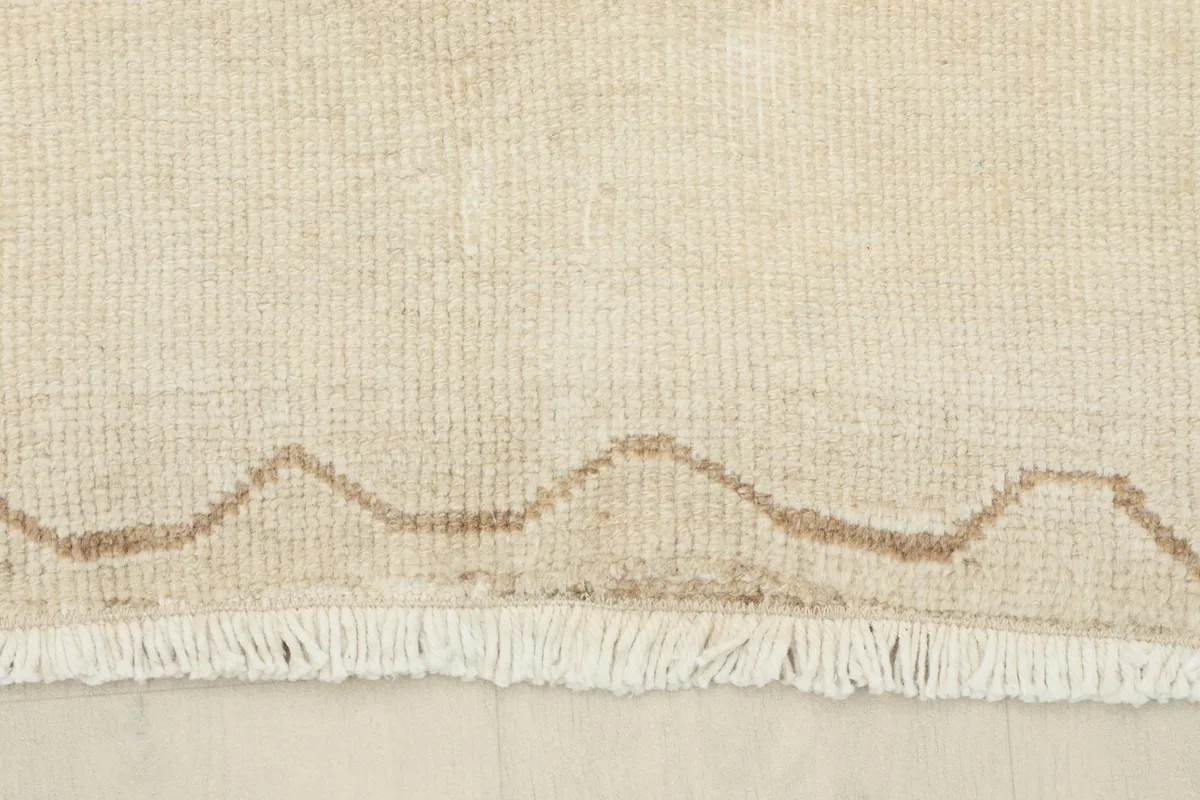 Close-up of the short, textured fringe and the subtle border design at one end of the runner.