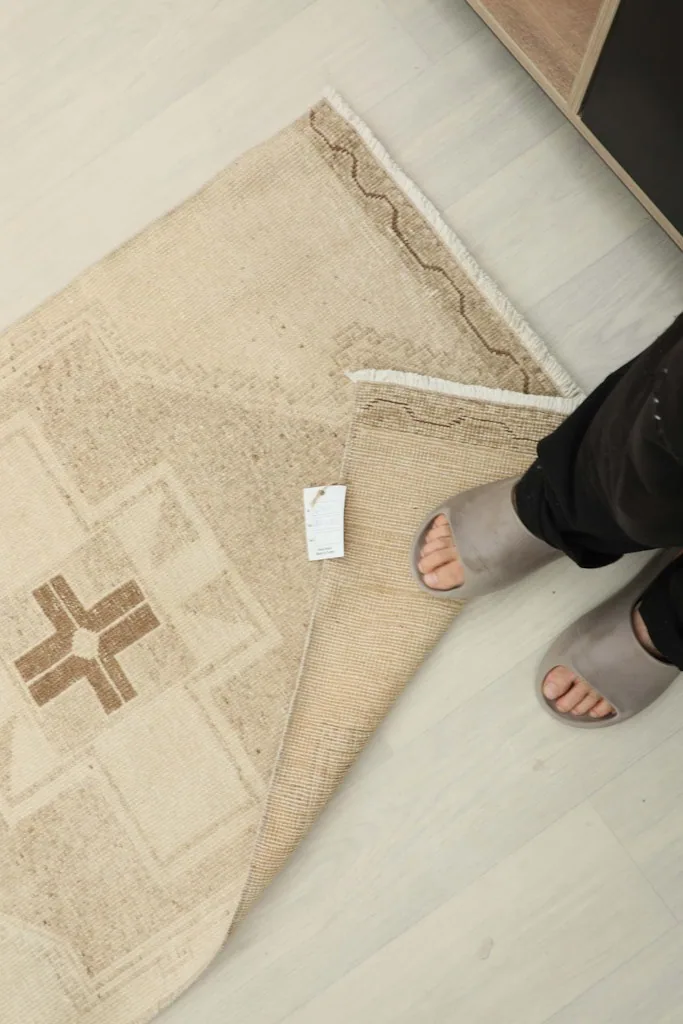 Overhead view showing the rug's label and a person's feet for scale.