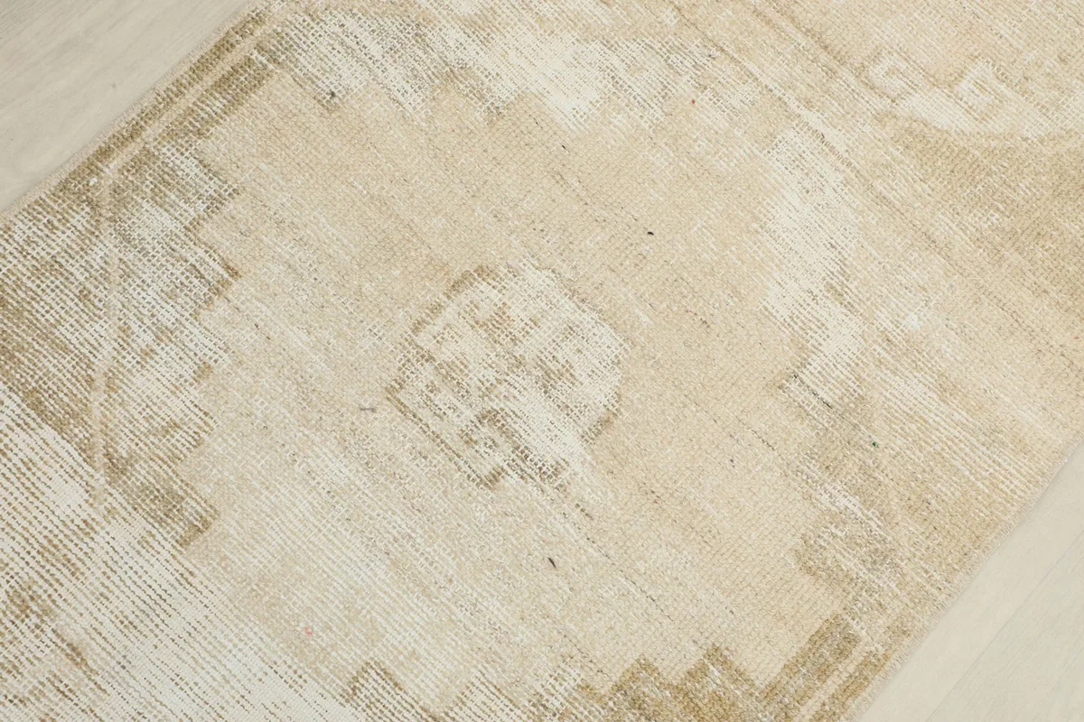 Detailed view of the distressed beige pile and a central geometric motif