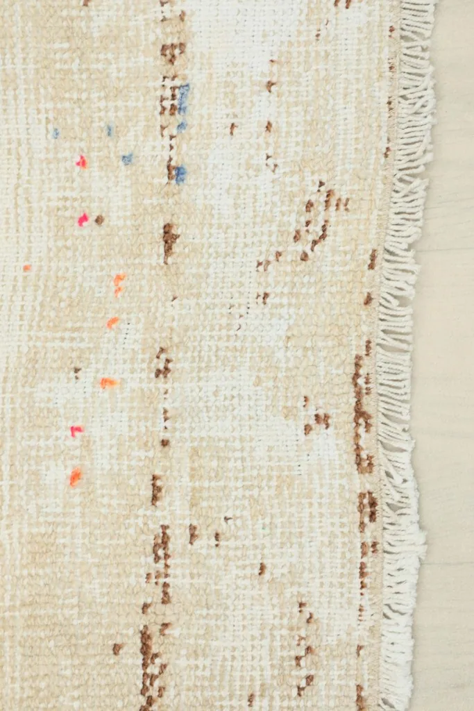 Close-up of the short, worn fringe and visible cotton foundation with small color specks