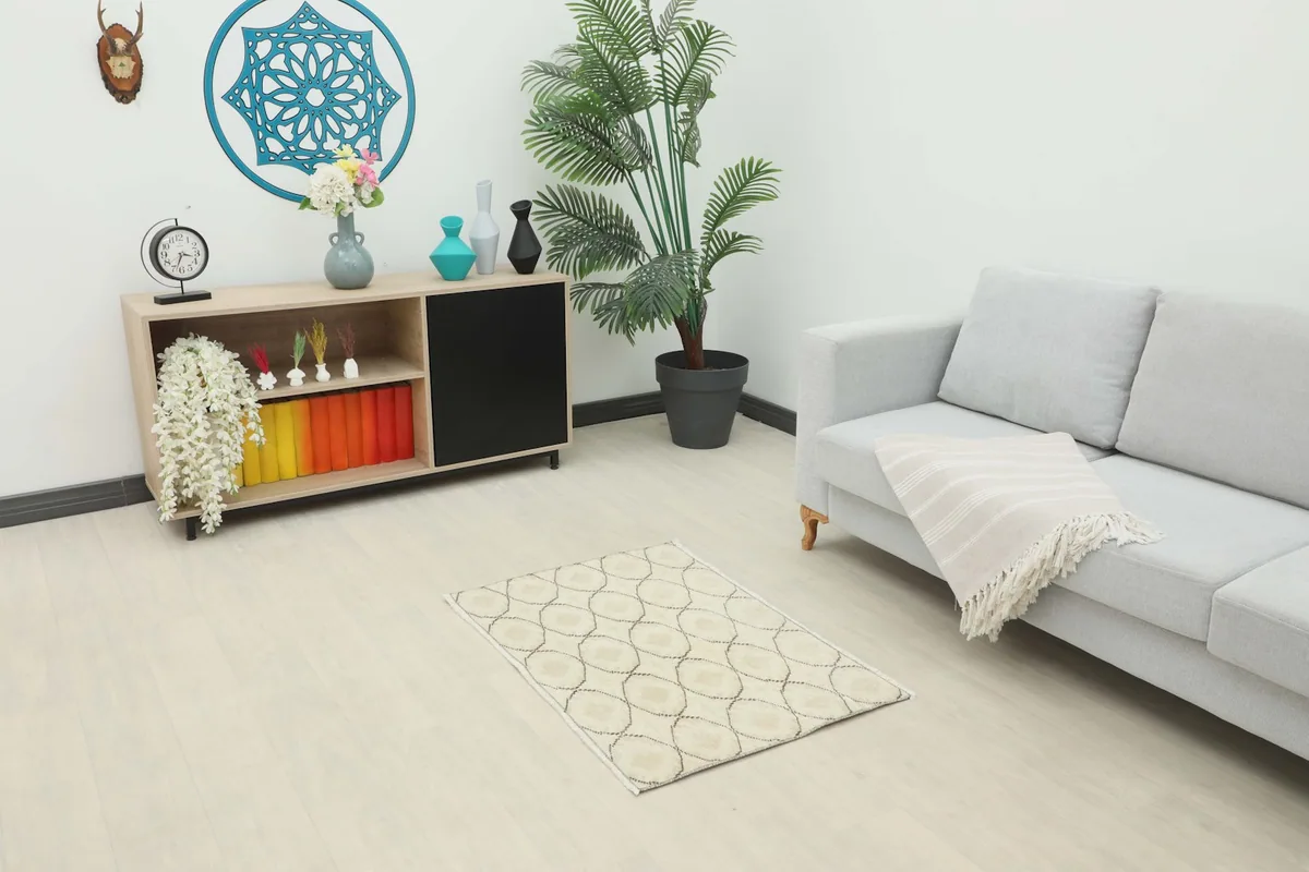 Cream and brown vintage rug placed in a living room setting with a sofa and cabinet