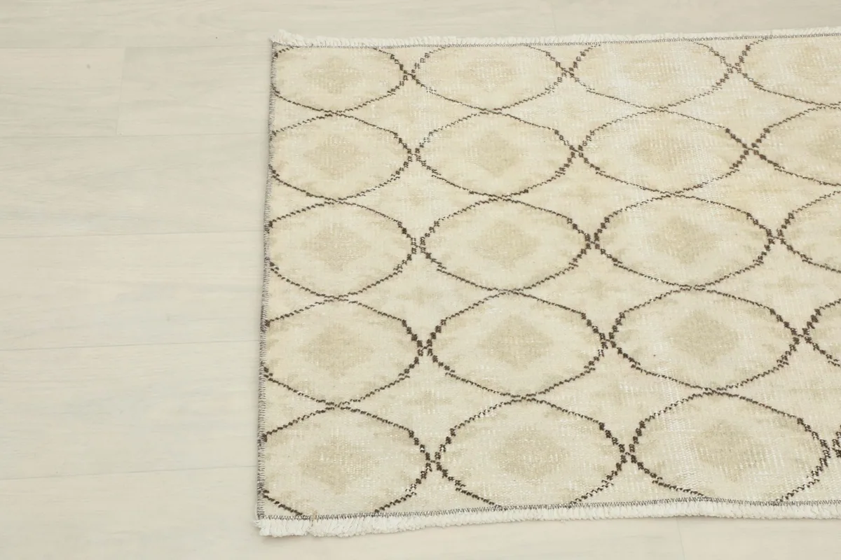 Detailed view of the interlocking brown geometric design on the cream rug