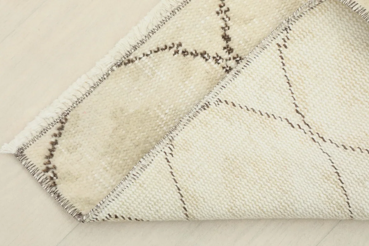 Corner of the rug folded to show the cotton foundation and reverse side