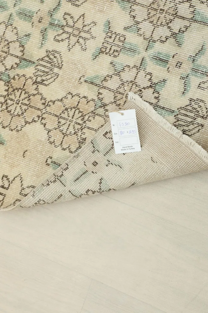 Underside of the rug with a product tag, showing the hand-knotted construction and cotton foundation.