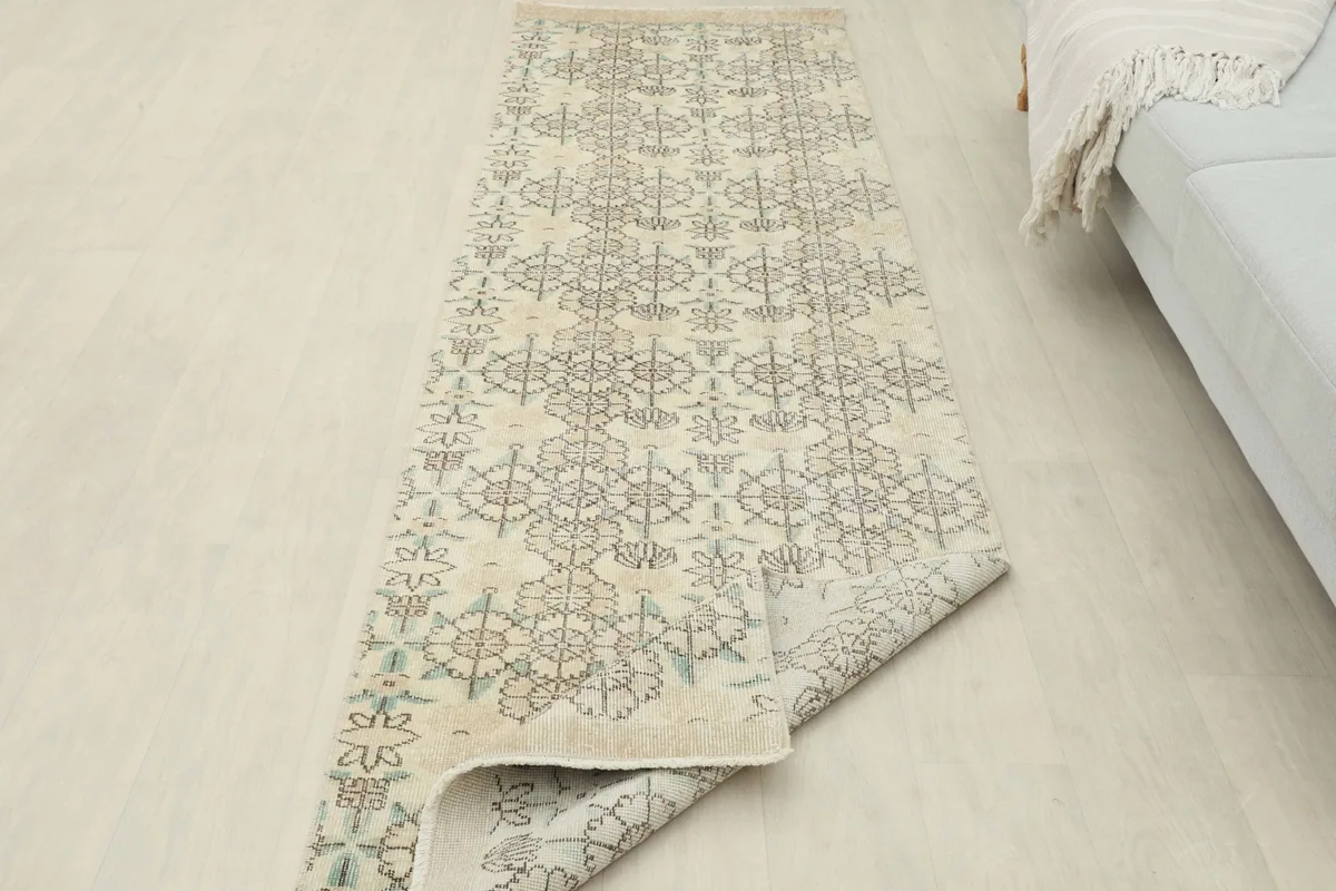 The runner rug partially rolled up, revealing the underside and the full length of the design.