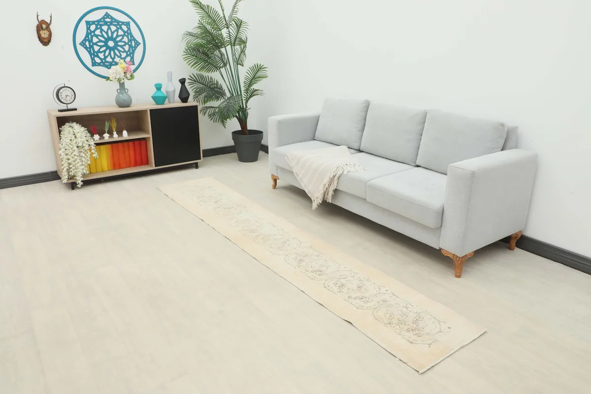 Beige runner rug extending along a modern living room floor next to a light gray sofa.