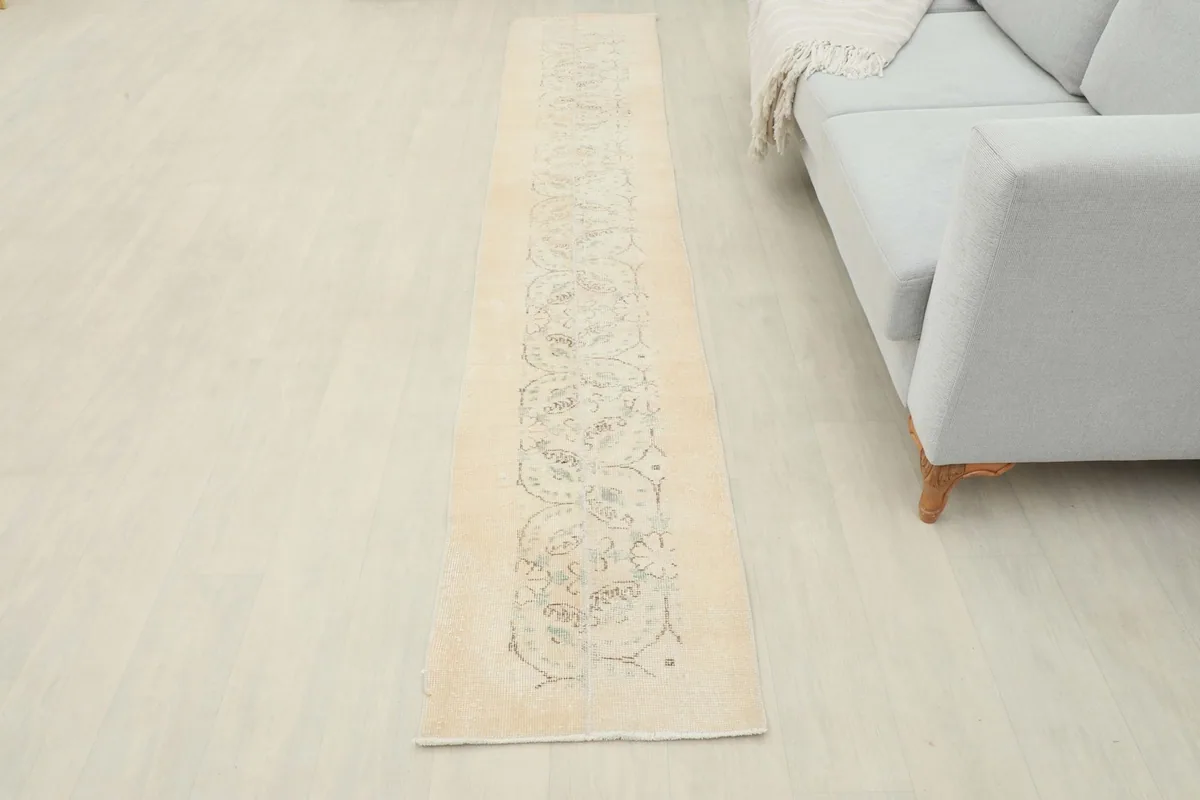 Overhead view of the beige runner rug in a room, positioned along the floor next to a sofa.
