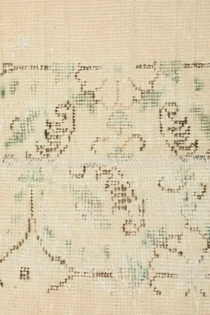 Extreme close-up of the faded green and brown motifs, highlighting the wool texture.