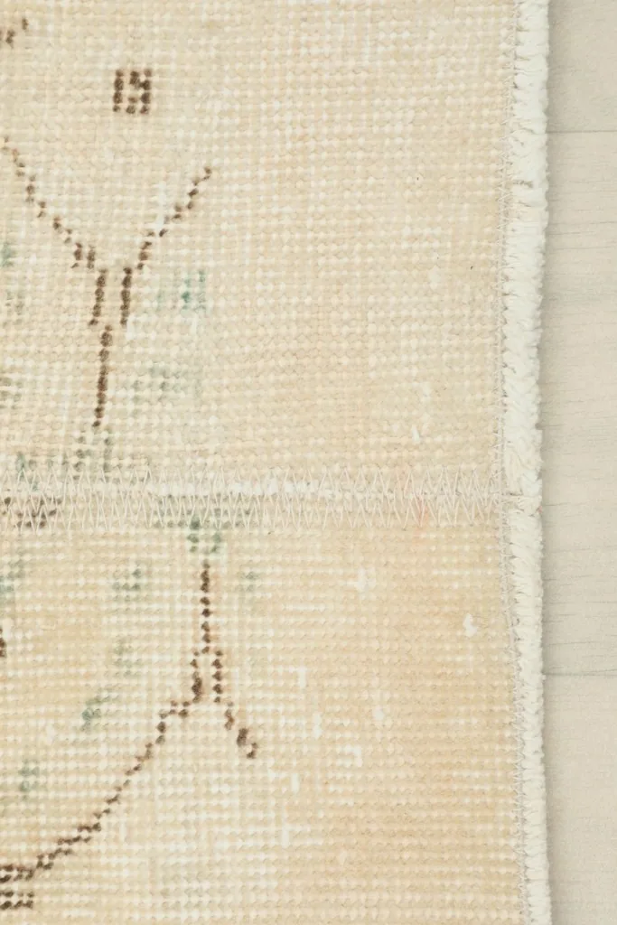 Close-up of the rug's side edge and fringe, showing the cotton foundation and hand-knotted construction.