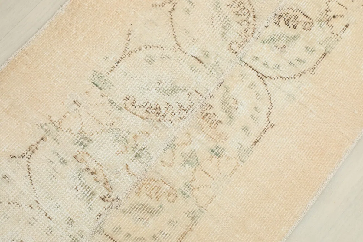 Detailed view of the low wool pile and the intricate, faded hand-knotted design.