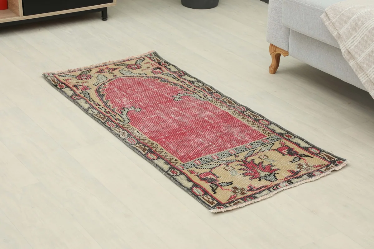 Angled view of the red and beige vintage rug, showing its full length and patterns