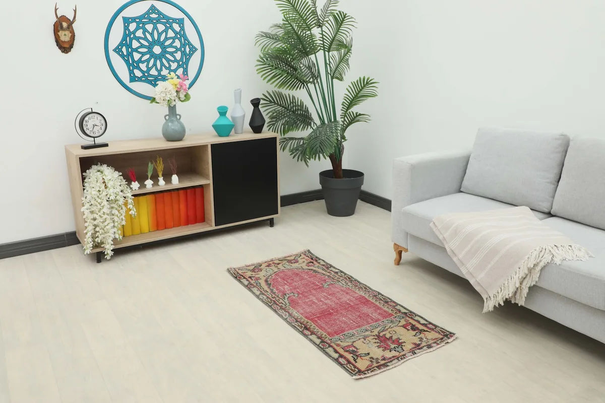 Vintage red Anatolian rug placed in a modern living room setting with a sofa and cabinet