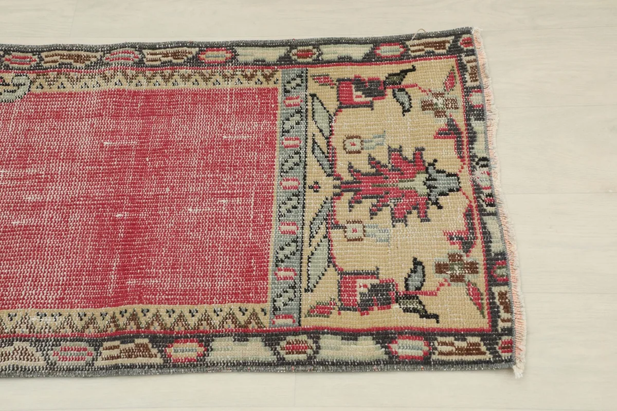 Close-up view of the lower section of the rug, highlighting beige tribal motifs and red field