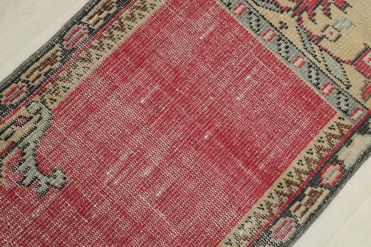 Detailed overhead shot of the rug's red field and surrounding geometric border