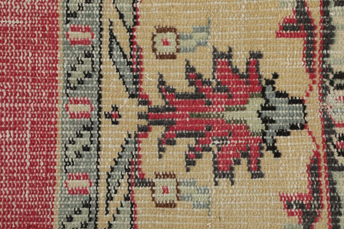 Macro detail of the hand-knotted wool pile and tribal patterns in beige, red, and gray