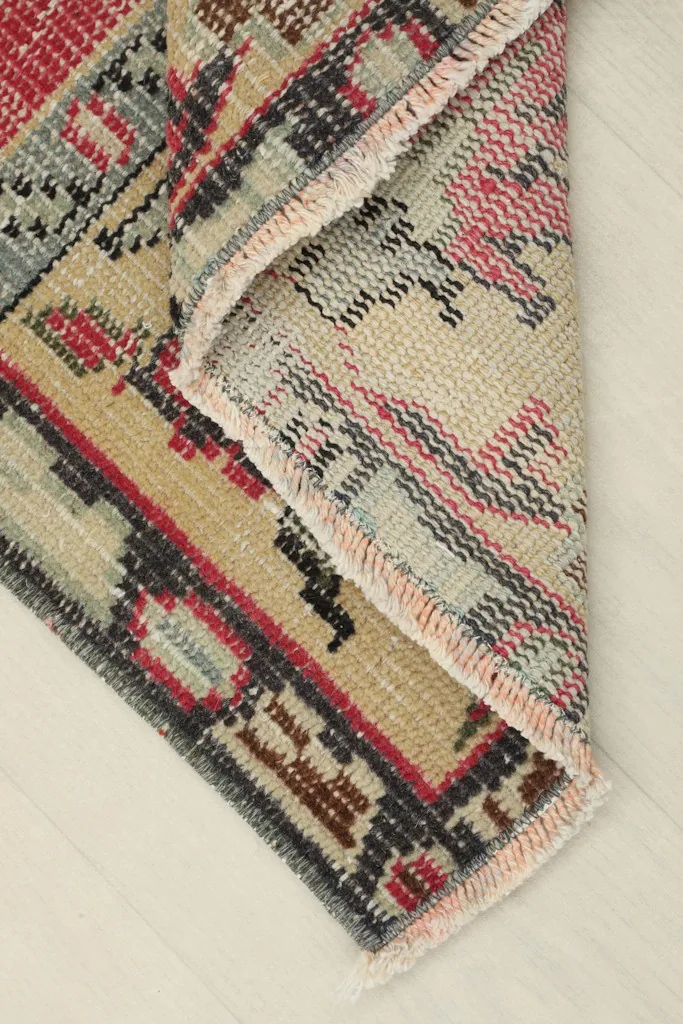 Corner of the rug folded to show the back, revealing the hand-knotted cotton foundation