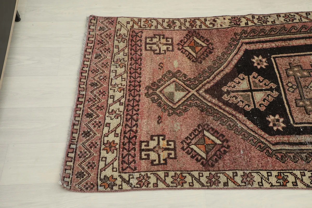 Detail view of the rose and brown motifs, showing the edge of the rug