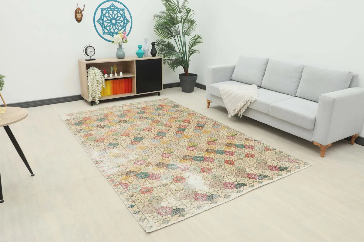 Vintage multicolor floral rug displayed in a living room setting with a sofa and cabinet.