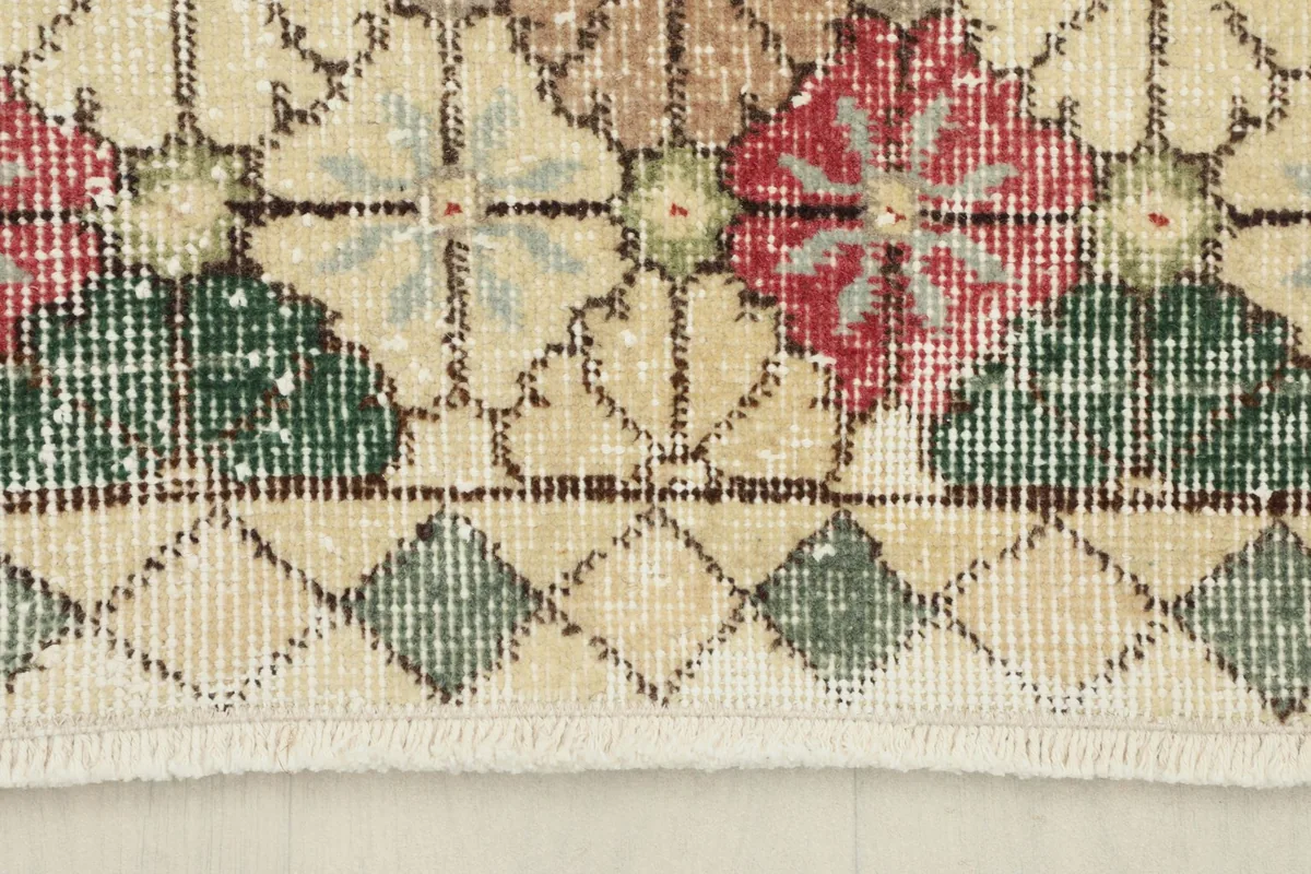 Detail of the rug's border and fringe, showcasing the cream and geometric diamond patterns.