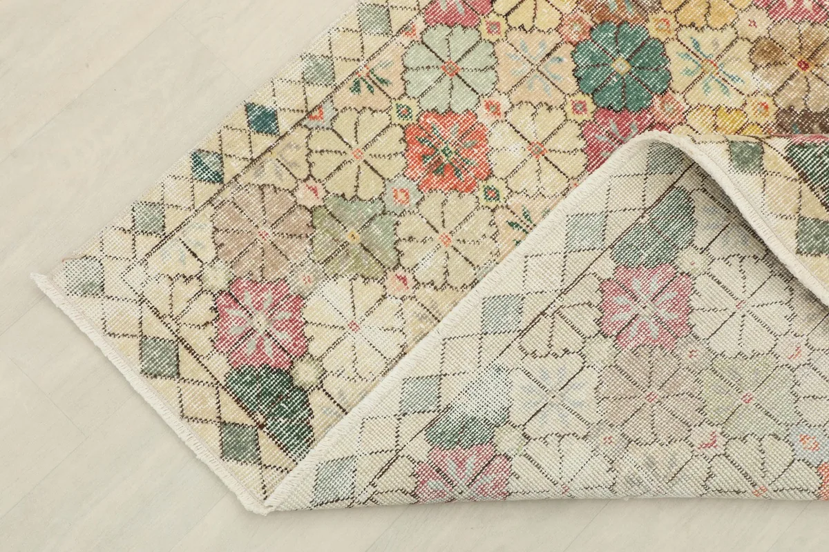 View showing the back of a folded corner of the rug, revealing the cotton foundation and knotting.