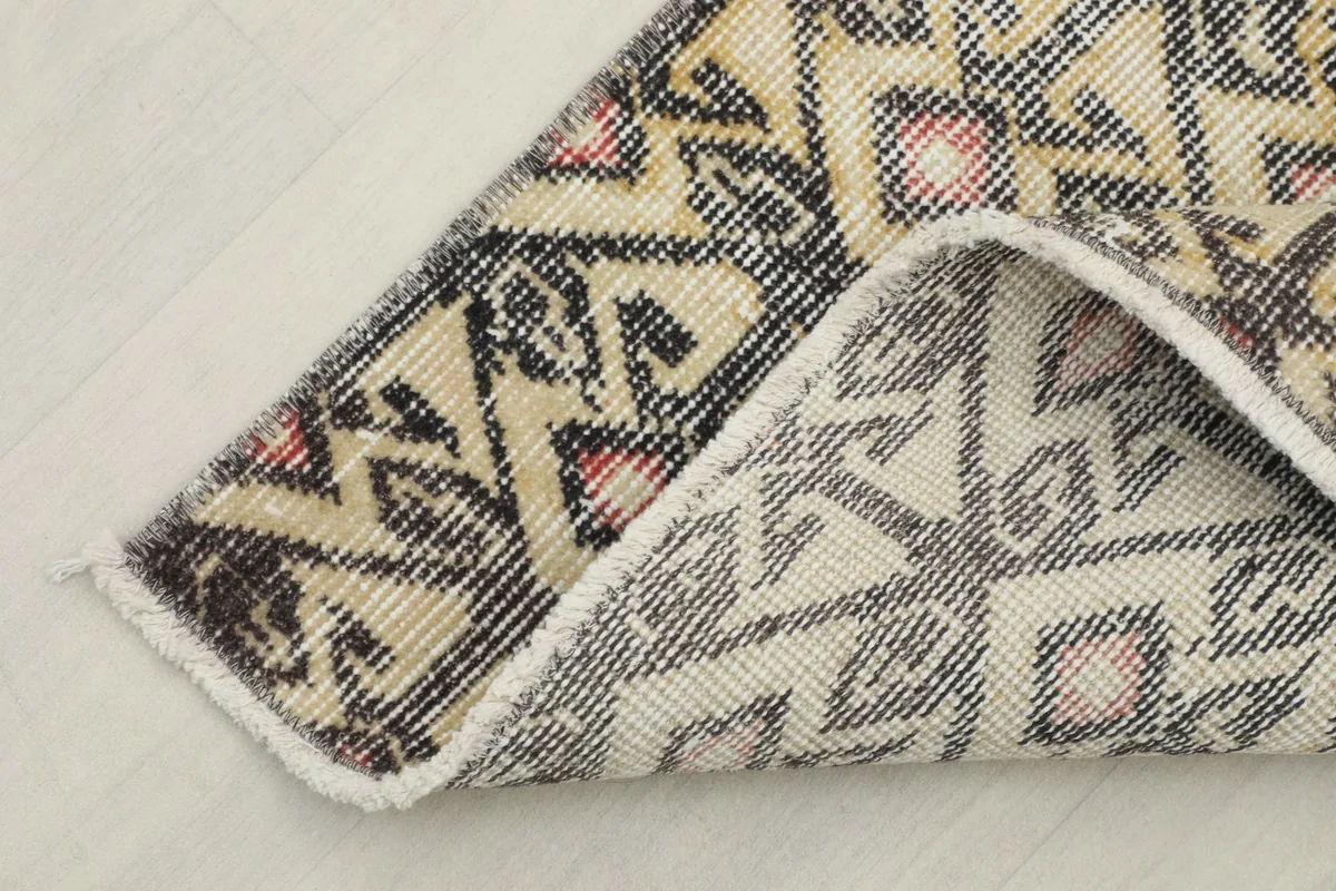 Corner of the rug folded to reveal the cotton foundation and reverse side of the knots
