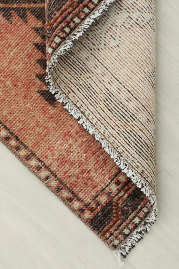 Corner of the runner folded back to reveal the cotton foundation and hand-knotting