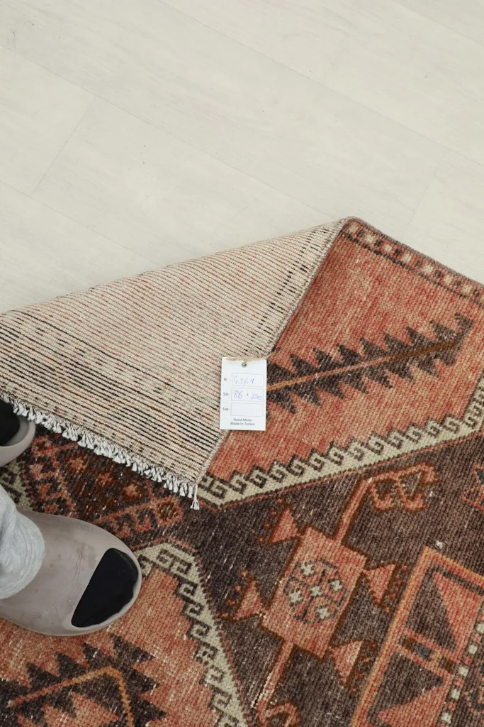 Overhead view of the rug's back with a tag, highlighting the wool pile and cotton foundation