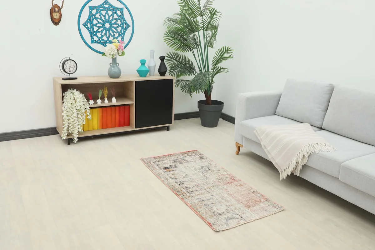 Vintage Anatolian rug placed in a modern living room setting, showing its scale next to a sofa