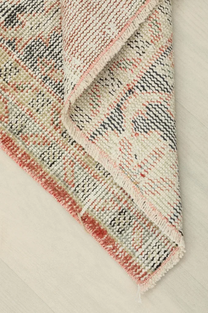 Corner of the rug folded back, displaying the wool pile on cotton foundation