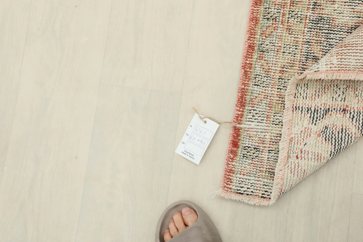 Rug with a size tag next to a foot for scale, emphasizing its mini area rug size