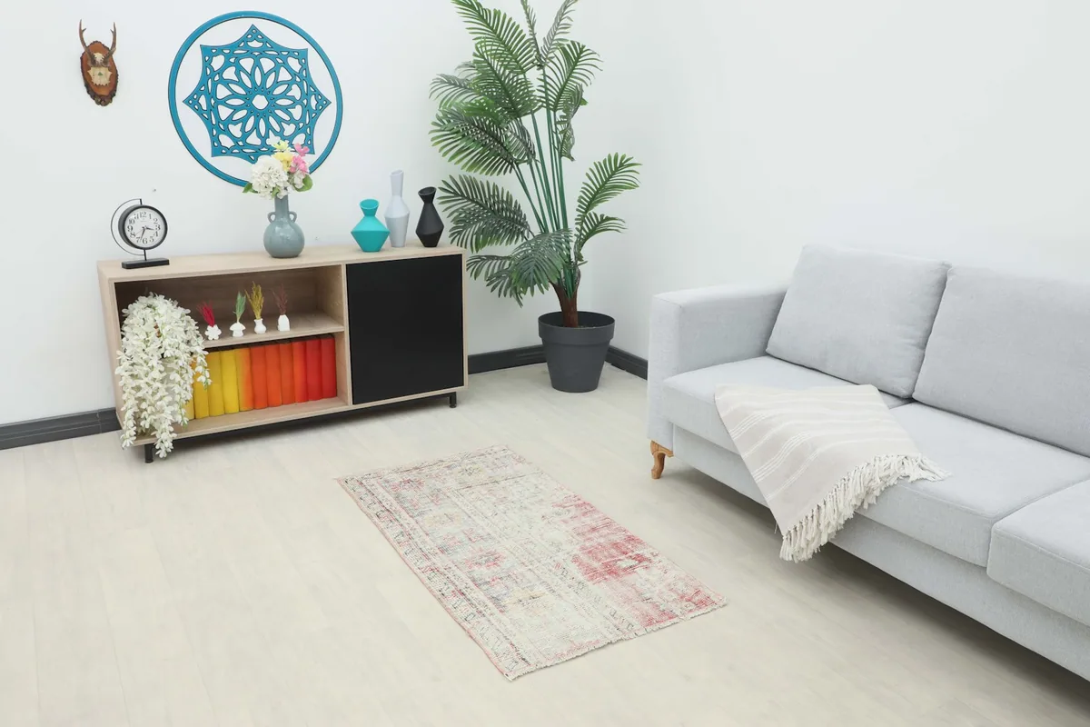 Vintage cream and red geometric rug placed in a modern living room setting with a gray couch.