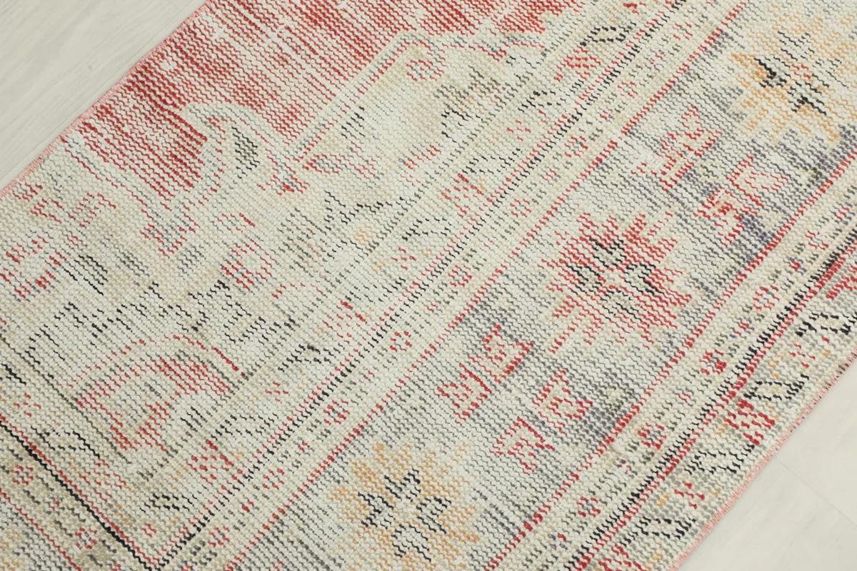 Mid-section detail of the rug, showcasing the interplay of cream, red, gray, and yellow in the pattern.