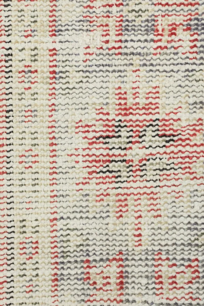 Extreme close-up of the low pile, showing the texture and individual knots of the wool rug.