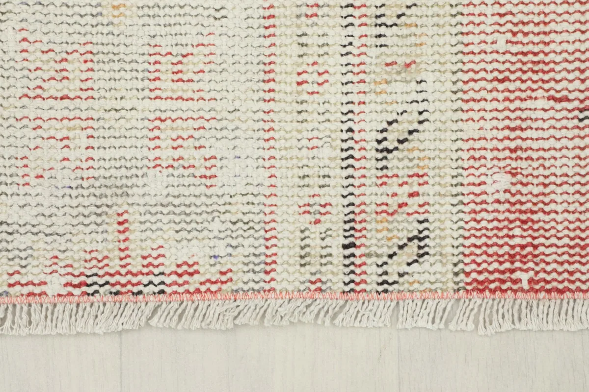Close-up view of the short, hand-finished fringes on one end of the vintage area rug.