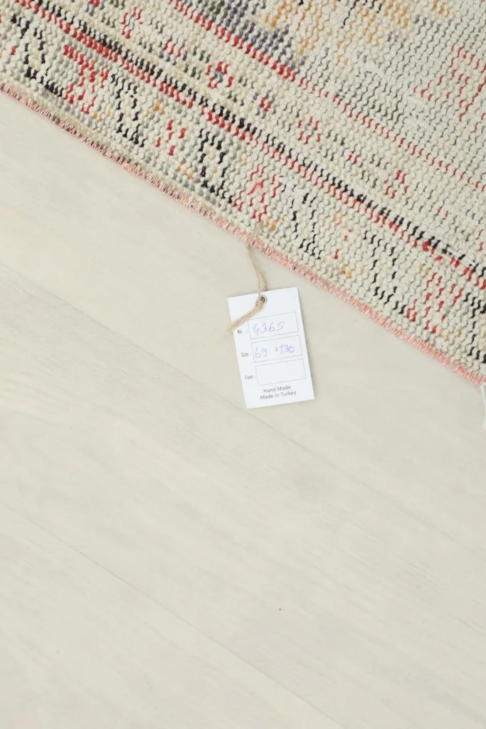Brand tag attached to the corner of the rug, indicating its origin and material.