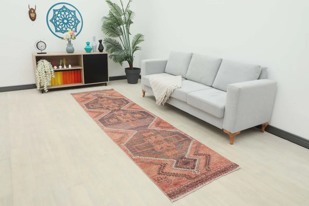 Runner rug placed in a living room setting next to a light gray sofa and dark wood cabinet.