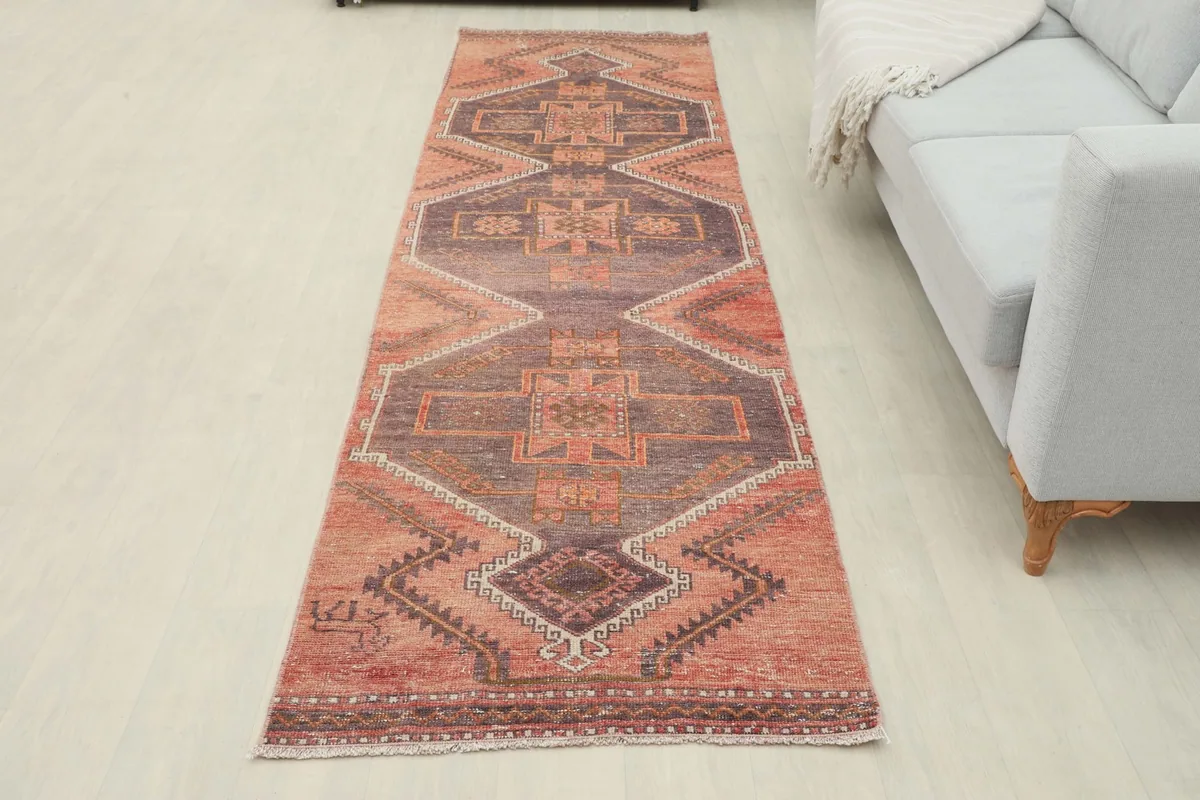 Full overhead view of the rust and brown geometric runner rug in a room with a light gray sofa.