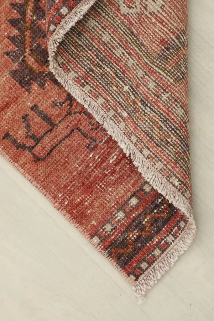 Corner of the runner rug folded back, showing the wool pile and cotton foundation.