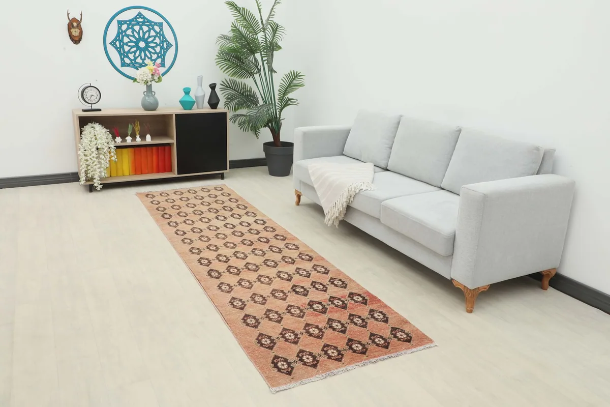 Runner rug in a living room setting, extending from a shelf unit towards a light gray sofa