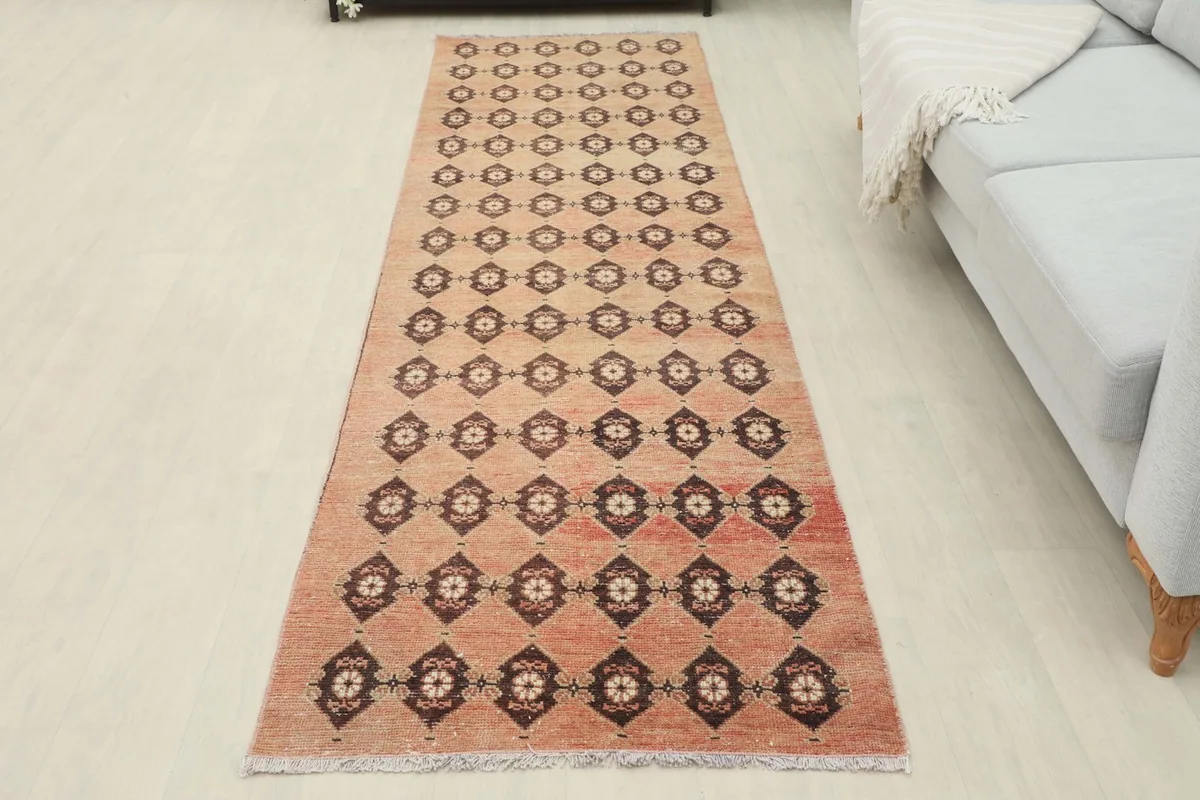 Full view of the rust runner rug in a room, laid out along a wall next to a sofa