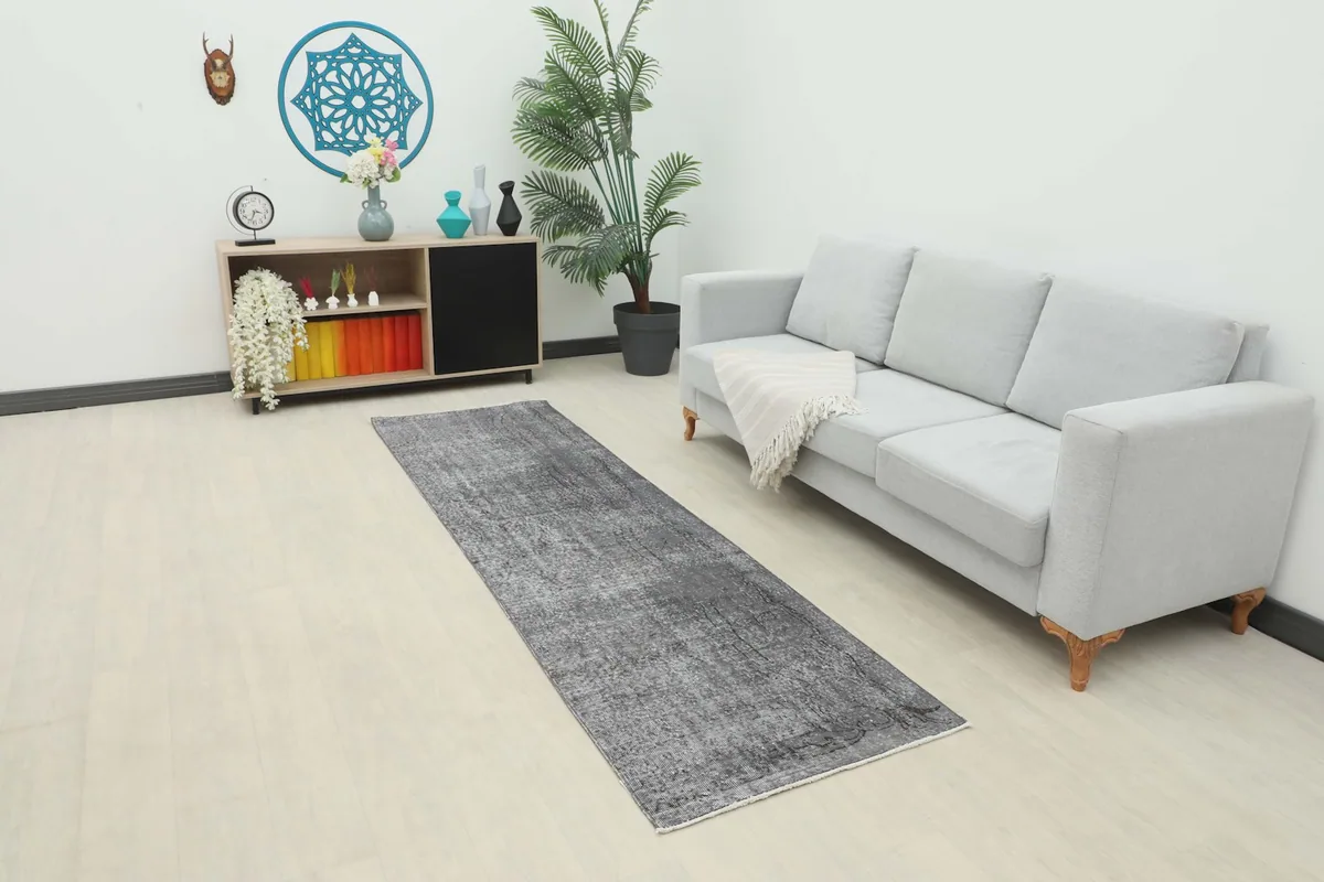 Runner rug in a living room setting, extending from a sofa towards a cabinet